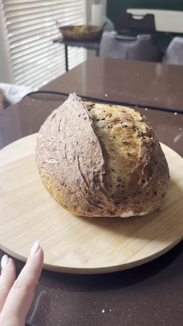 Golden blistered seeded sourdough batard on a wooden board